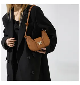 Chic brown crescent shoulder bag featuring an elegant metallic butterfly clasp, perfect for daily wear.