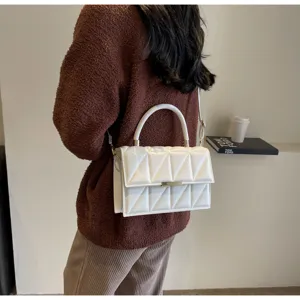 Detailed view of white quilted shoulder bag with top handle and gold hardware accent.