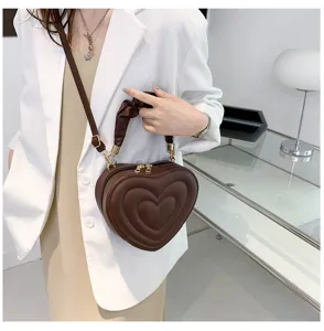 Detail shot of the brown heart-shaped crossbody bag featuring pleated handle and strap.