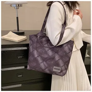 Close-up of stylish purple quilted tote bag with handle and brand label in clean lifestyle room.