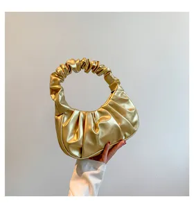 Golden metallic ruched hobo shoulder bag detail, stylish underarm dumpling pouch close-up view