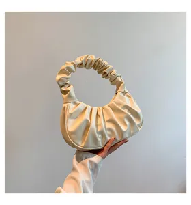 Detail shot of elegant cream ruched cloud dumpling handbag, soft leather handle texture.