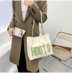 Detailed view of the stylish women's PU leather tote bag with green letter prints and chain straps.