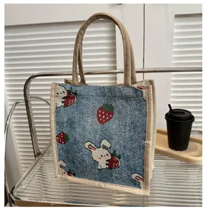 Close-up shot of the blue linen tote bag featuring cute rabbit and strawberry woven details.