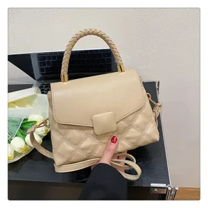 Detail view of a stylish beige quilted crossbody bag with a chic braided top handle.