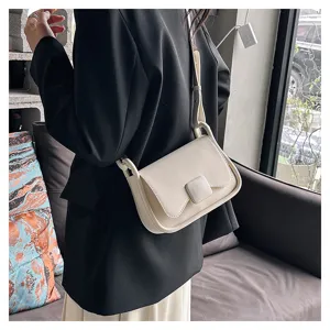 Gros plan d'un sac à épaule minimaliste couleur crème porté avec un blazer noir chic.
