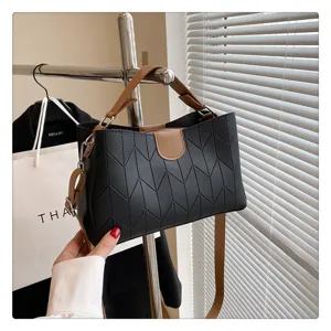 Detail shot of stylish black chevron handbag with brown handles and strap on rack.