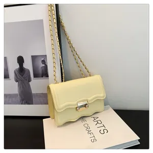 Detail view of the stylish yellow wavy chain shoulder bag with elegant metal lock clasp.