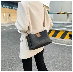 Detail view of the elegant black chevron shoulder bag worn outdoors with stylish outfit.