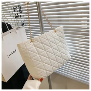 Detail view of white quilted bag featuring gold chain strap and clean texture.