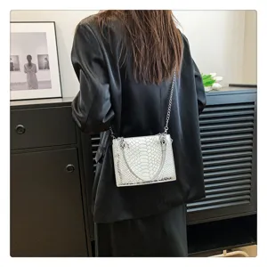 Vue détaillée du sac bandoulière chaîne motif croco vernis pour femme en scène de style.