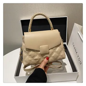 Detailed view of chic beige quilted handbag with braided handle and elegant flap closure.