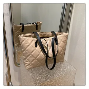 Stylish quilted tote bag detail in beige with black handles, elegant minimalist style.