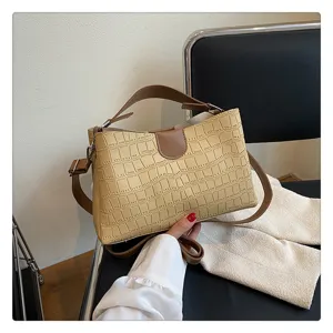 Detailed view of the stylish beige crocodile pattern handbag with brown leather handles and straps.