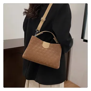 Brown textured shoulder bag detail showing geometric pattern, beige flap closure, and strap.