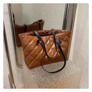 Brown quilted tote bag with black handles on clear display stand, stylish casual daily handbag.