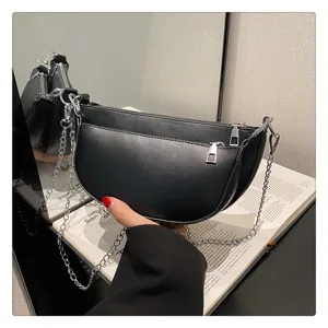 Detailed view of black leather saddle shoulder bag with silver chain strap and front pocket.