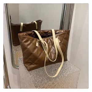 Detailed view of brown quilted tote bag with beige straps showcasing premium stitching texture.