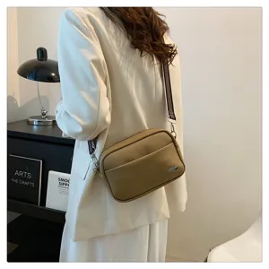 Detail shot of a stylish PU leather crossbody bag with a wide strap, shown in a modern setting.