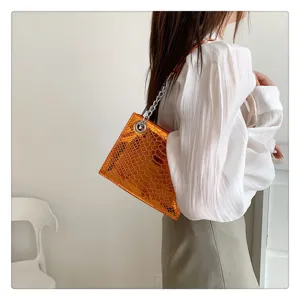 Détail de sac bandoulière à motif serpent métallisé orange, bandoulière chaîne élégante.