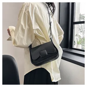 Vue détaillée d'un élégant sac à bandoulière noir en cuir porté par un mannequin.