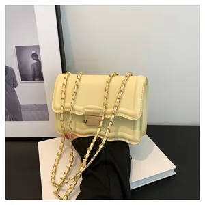 Close-up detail shot of butter yellow wave-edged flap bag with metal chain strap and lock.