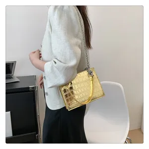Detailed view of the shiny gold metallic crocodile pattern chain handbag worn by model.