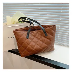 Brown quilted tote bag detail view, showing soft diamond pattern and durable black shoulder straps.