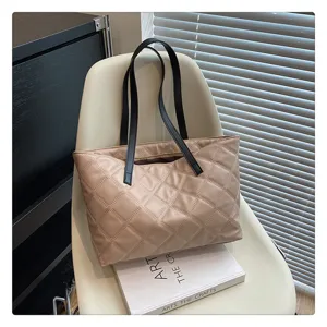 Details of the beige quilted tote bag showing fine stitching, black handles and zipper.