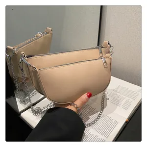 Detailed shot of a stylish light khaki saddle bag with double zippers and silver chain strap.