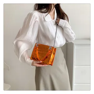 Detail close-up of the stylish orange laser stone pattern chain crossbody bag and handle.