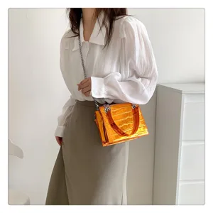 Orange metallic crocodile pattern chain crossbody bag detail shot showing stylish wear.