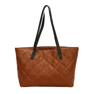 Brown quilted tote bag detail showing fine stitching and durable black shoulder straps.
