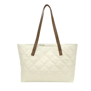 Quilted tote bag with brown straps, detailed view showcasing diamond stitching texture.