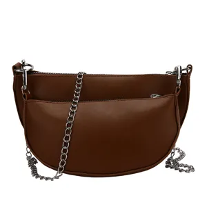 Detail view of brown PU leather saddle bag with silver chain strap and double pocket design.