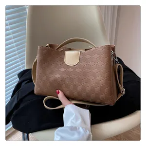 Detail view of a stylish brown geometric PU leather handbag with top handle and crossbody strap.