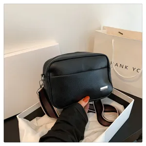 Detailed close-up view of black PU leather crossbody bag with wide strap and compact design.