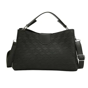 Detailed view of black PU leather handbag with geometric embossed pattern, top handle and strap.