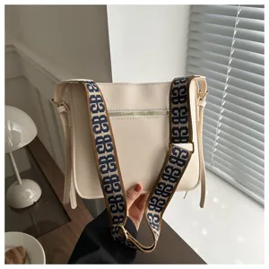 Detailed view of women's beige shoulder bag with stylish wide monogram patterned strap.