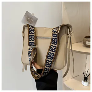 Detailed view of a stylish beige crossbody bag featuring a wide patterned strap and clean design.
