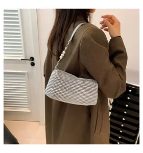 Sparkling rhinestone shoulder bag for women, elegant cylindrical underarm purse with pearl strap.