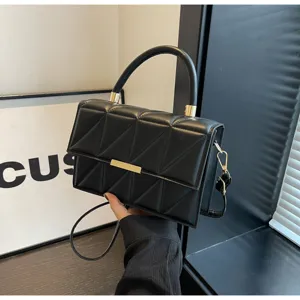 Black quilted structured mini handbag detail shot with top handle and chic metal clasp.