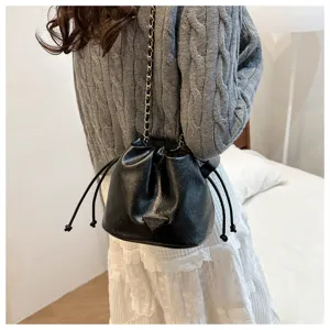 Detailed view of women's black faux leather bucket bag with chic chain strap and drawstring.