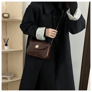 Detail shot of retro brown crossbody bag with gold turn-lock closure and stylish strap.