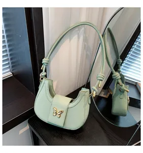 Close-up view of a chic mint green underarm shoulder bag featuring a gold butterfly clasp.