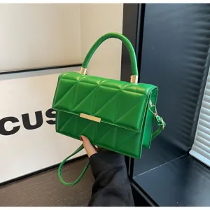 Green quilted shoulder bag detail showcasing triangular stitching and gold hardware accent.