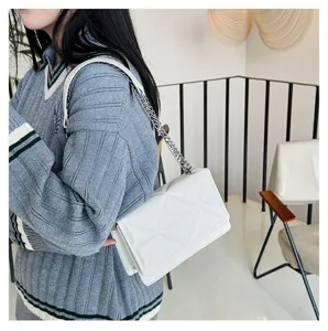 Nahaufnahme einer eleganten weißen gesteppten Umhängetasche mit Metallkette, modern.