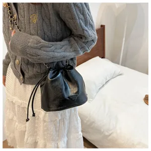 Black leather bucket bag with chain strap and drawstring closure for women daily use.