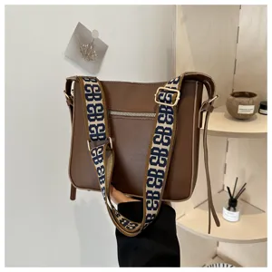 Brown leather shoulder crossbody bag for women with wide patterned strap daily commuter bag.