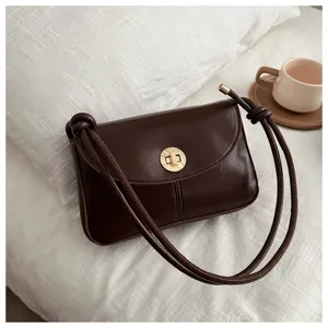Detailed view of the retro dark brown small shoulder bag showing its elegant metal twist-lock.